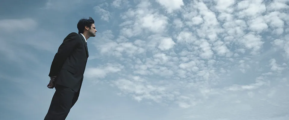 Ein Mann im Anzug mit Himmel im Hintergrund