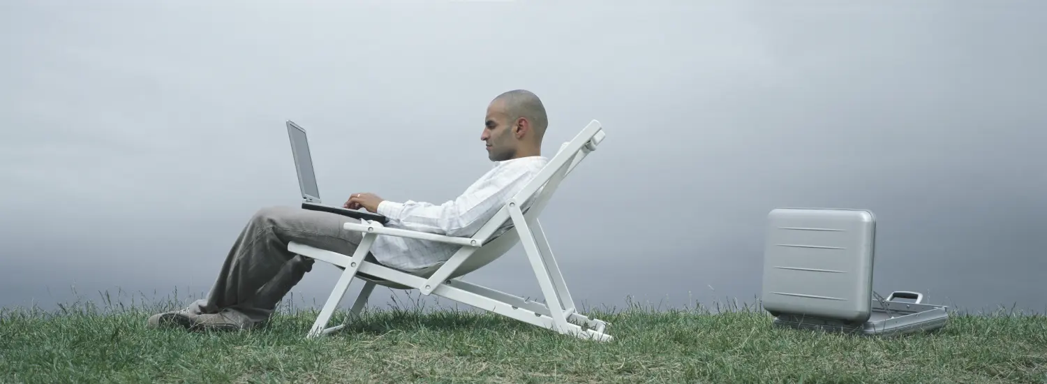 Mann sitzt auf einer Couch und arbeitet am Laptop