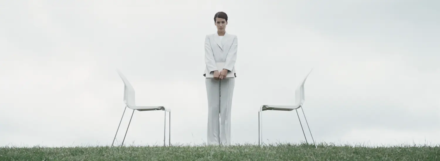 Frau steht zwischen zwei weißen Stühlen